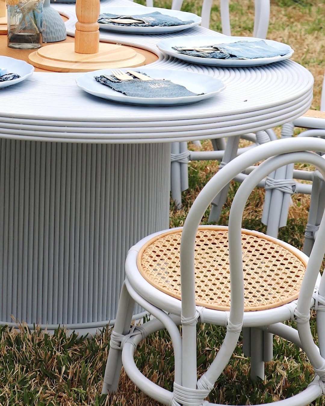 Side view of pastel rattan dining table with bamboo-style cafe chairs