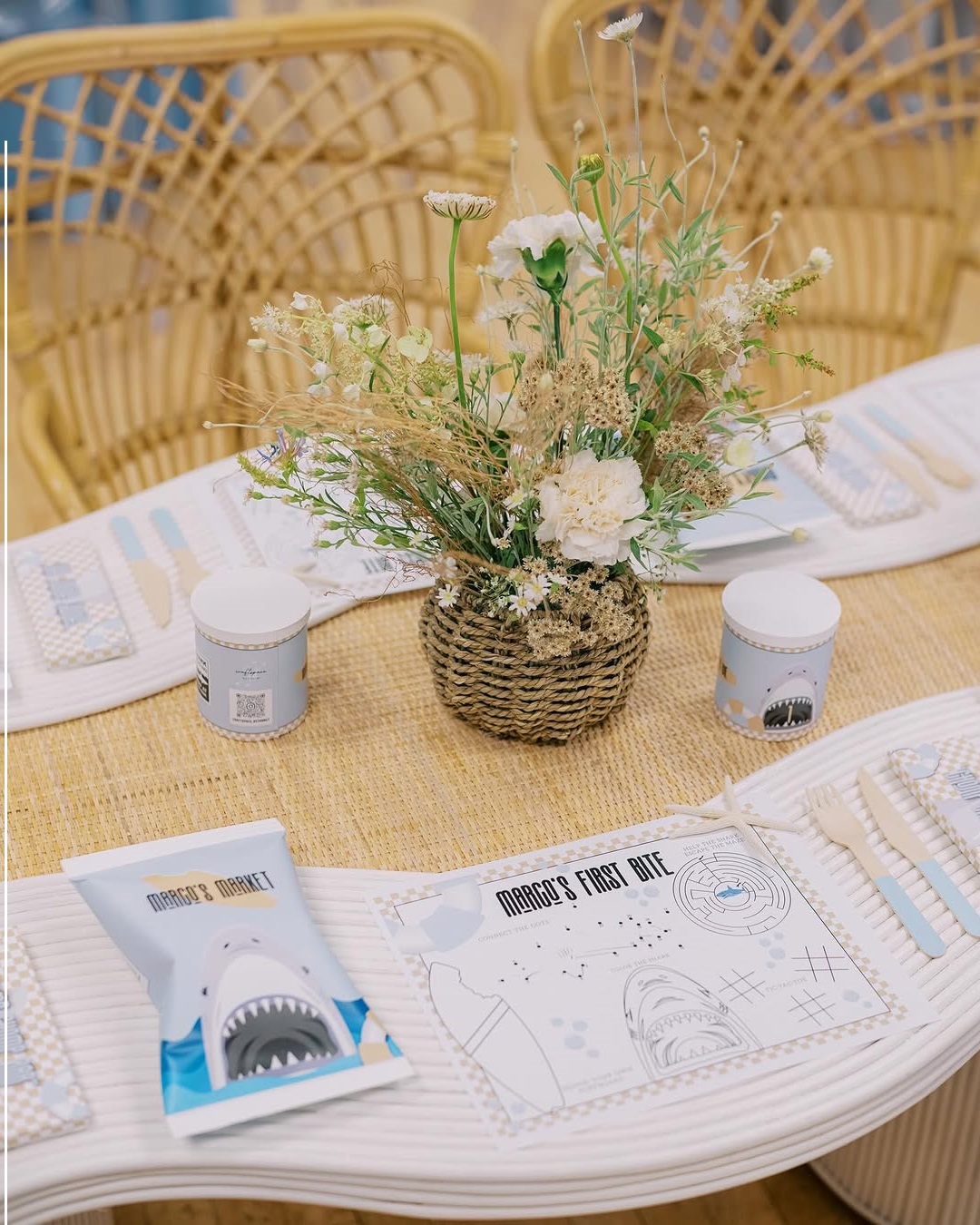 Overhead look at long pastel blue rattan table set for kids party