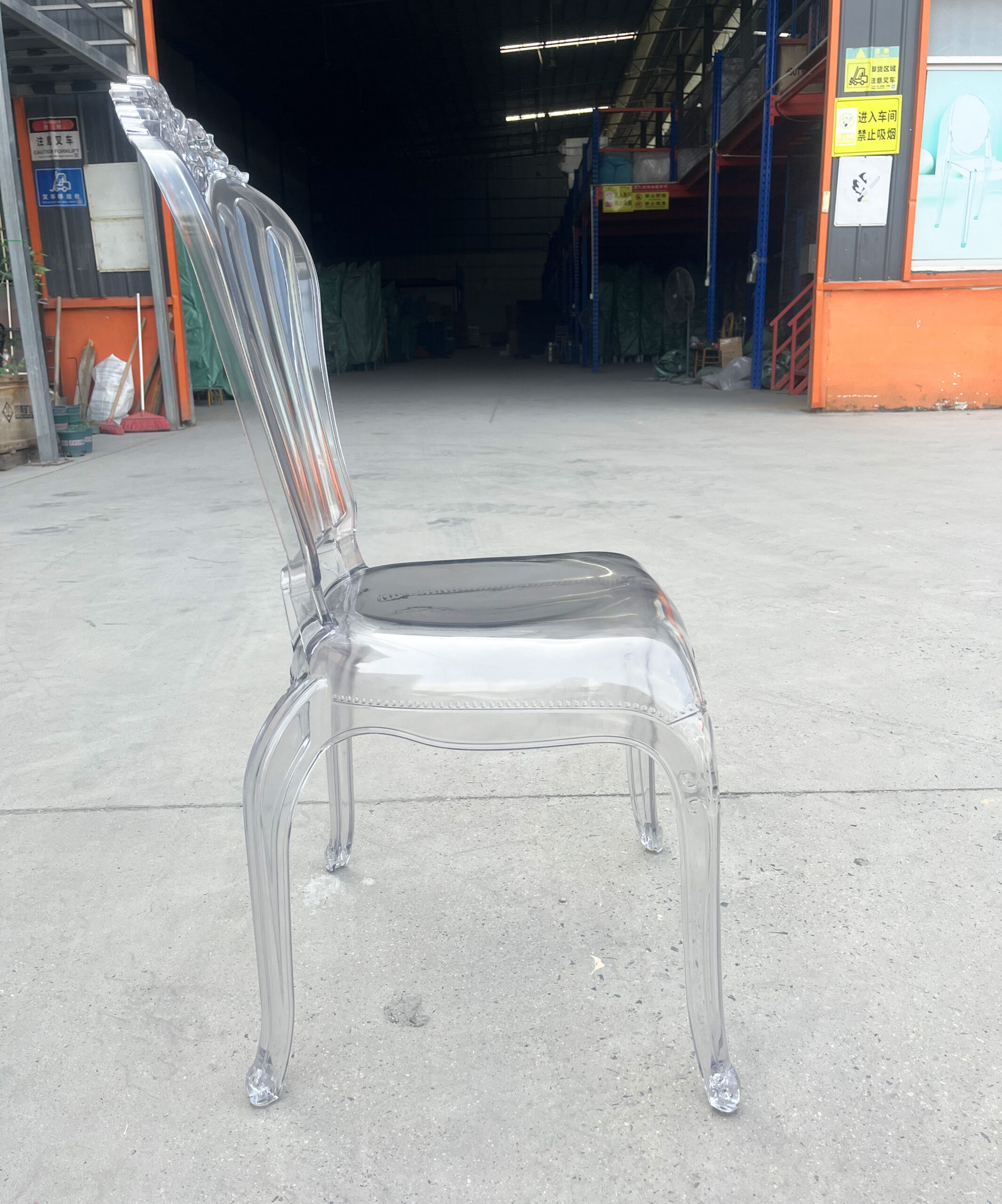 Side view of a transparent Baroque-style acrylic chair with curved legs and fluted backrest
