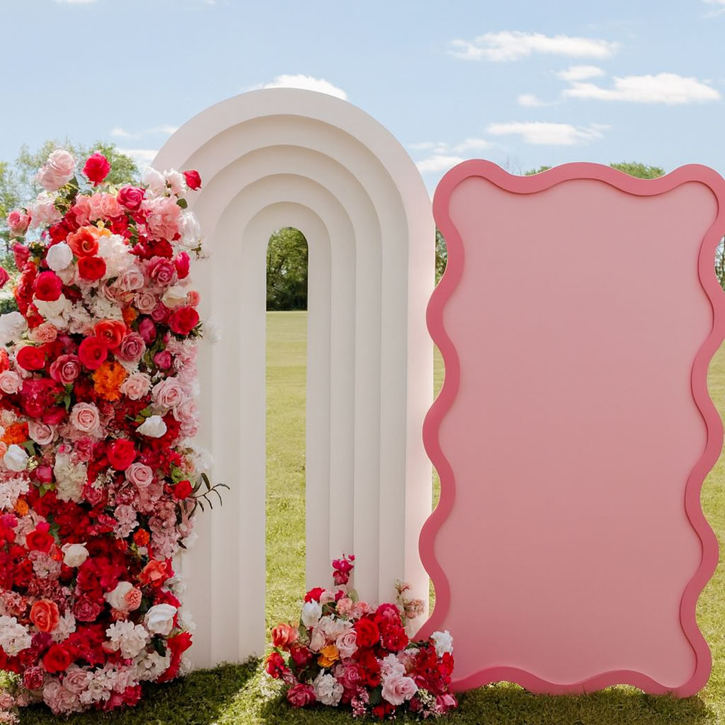 White layered PVC backdrop arch decorated with flowers at a wedding ceremony
