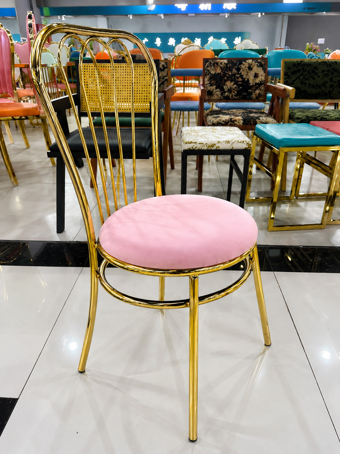 Luxury gold wedding chair with pink velvet cushion and mirror electroplated metal frame in furniture showroom
