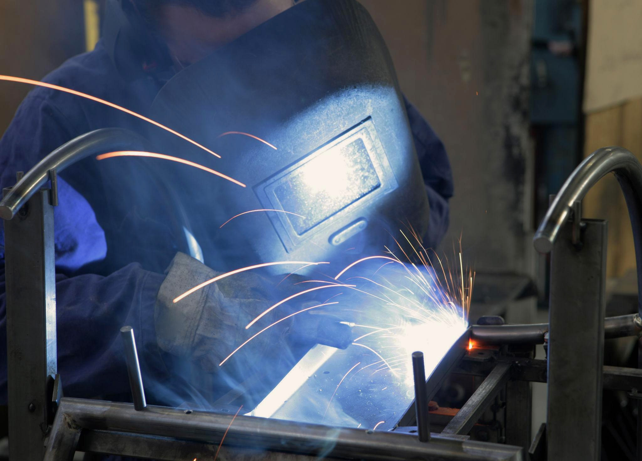 factory worker welding metal furniture frame showing real production behind Alibaba suppliers