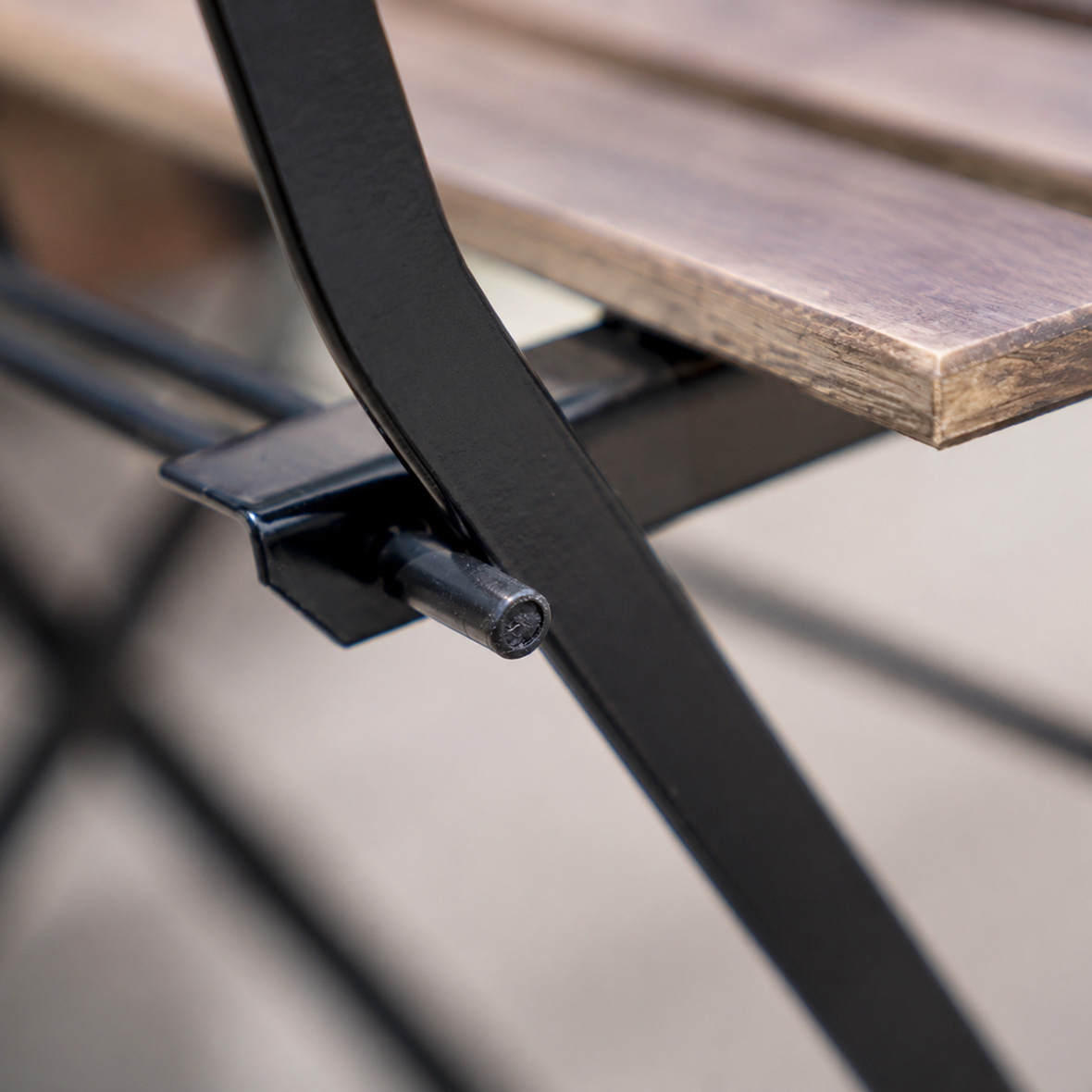 Close Up Detail of Rustic Wood Slatted Bistro Folding Chair Metal Frame and Folding Lock Mechanism