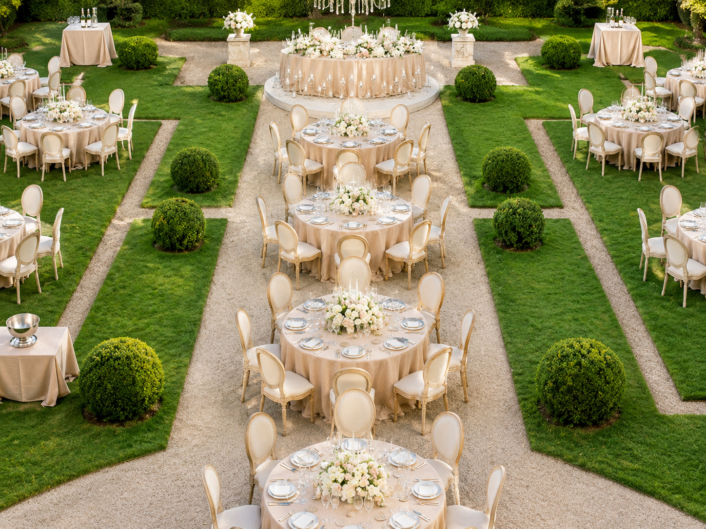 Stackable Louis XVI oval back chairs arranged around elegant round banquet tables at a luxury outdoor garden wedding reception venue
